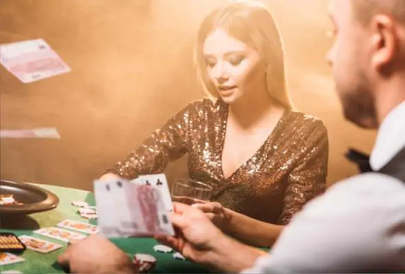 Two people playing cards at a casino table with flying cards, symbolizing Online Matchbox Betting ID and gambling excitement.